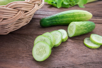 Fresh cucumber and slices on wooden table