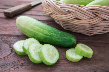 Fresh cucumber and slices on wooden table