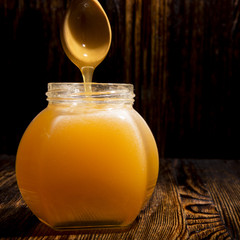 jar of honey and spoon on a wooden background