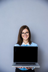 Smiling businesswoman showing blank laptop display