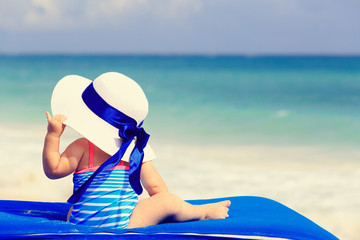 little girl in big hat on summer beach