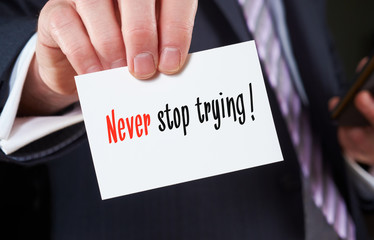 A businessman holding a business card with the words, Never sto