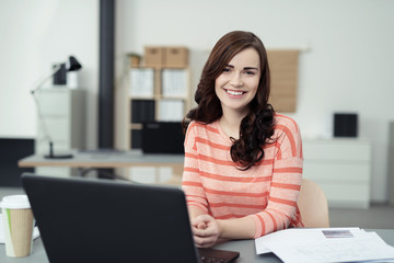 lächelnde frau an ihrem arbeitsplatz im büro