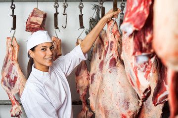 Female Butcher Hanging Meat In Butchery