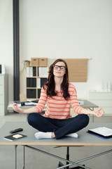 frau entspannt im lotus-sitz am arbeitsplatz