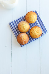Homemade muffins in blue napkin and jug of milk on wood table. S