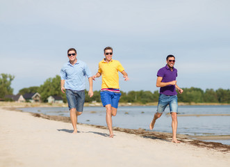 Fototapeta na wymiar smiling friends in sunglasses running along beach