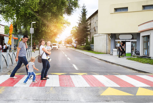 Young family with two boys in the city walking on a crosswalk