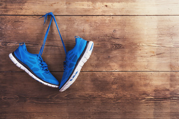 Pair of sneakers hang on a nail on a wooden fence background
