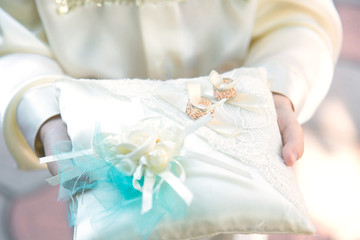 Two beautiful wedding rings on a cushion in the hands of a child