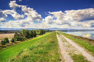 Gravel road along the shore of the lake with blue water