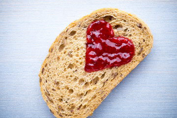 Grain slice of bread with jam heart shape.