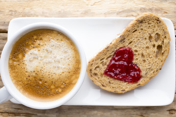 Fresh coffee. Grain slice of bread with jam heart shape.