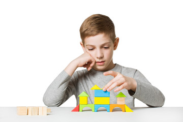 Portrait of a boy building house made of wooden blocks