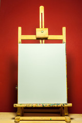 painting easel with white canvas for text in dramatic light