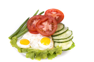 two fried eggs with vegetables on a plate