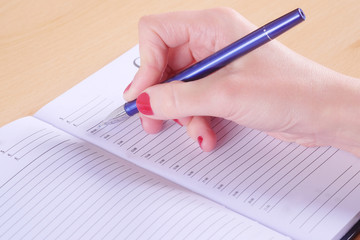 Female hand with pen and notebook