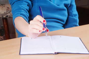 Female hand with pen and notebook