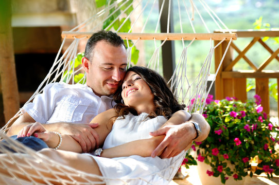 Young couple on a rope hammock in a cottage