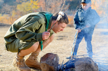 Boy Scout with Sausages on Stick by Campfire