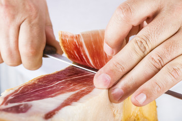 Profesional cortando lonchas de jamón serrano a cuchillo