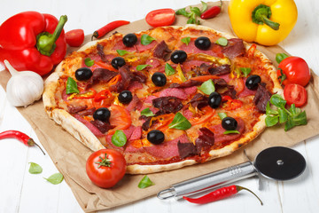 Pizza with salami, ham and black olives on wooden table