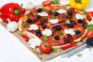 Pizza on white wooden table with tomato, ham, mushrroms