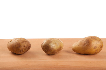 Three potatoes on wooden table
