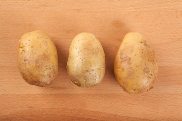 Three potatoes on wooden table