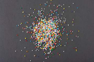Colorful round sprinkles spilled on black background, isolated