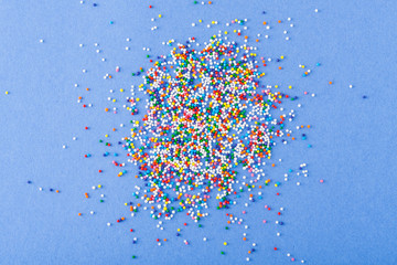 Colorful round sprinkles spilled on blue background, isolated