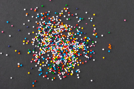 Colorful round sprinkles spilled on black background, isolated