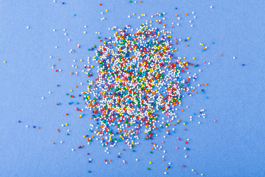 Colorful round sprinkles spilled on blue background, isolated
