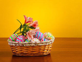 Fototapeta na wymiar Brightly colored eggs with flowers in a wicker basket