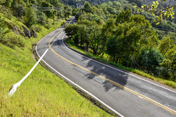Curved road with double yellow and telephone wires