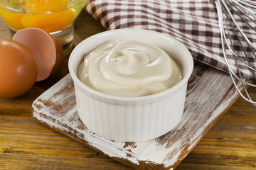 Mayonnaise in  a bowl with eggs  on  wooden background