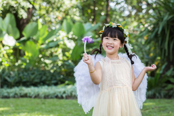 Little cute girl in angel dress with smiling face in the park