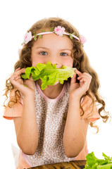 Beautiful healthy little curly girl enjoying eating lettuce