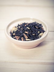 Bowl of dried green tea leaves on wooden background