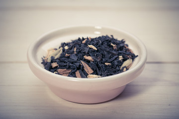 Bowl of dried green tea leaves on wooden background