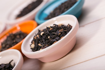 assortment of dry tea in small bowl, on wooden background