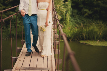 Fashionable cool wedding couple go on a wooden suspension bridge