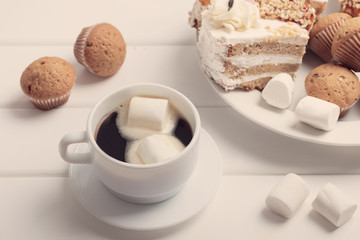 coffee with marshmallow and cake on white wooden background