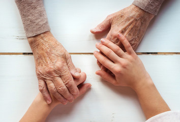 Unrecognizable grandmother and granddaughter holding hands