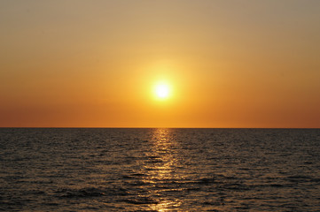blue sea and sky with the sun at dusk