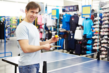 Man chooses table tennis racquet in shop
