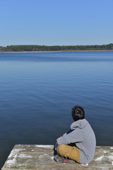 Fototapeta premium Young boy sitting on a thrown Lake