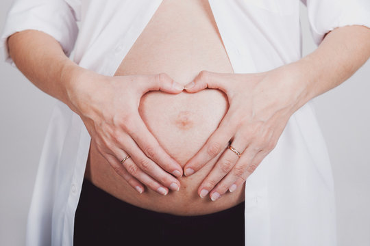 Woman holding her hands in a heart shape on pregnant belly
