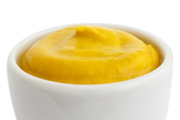 Small white ceramic dish of American mustard. Isolated.