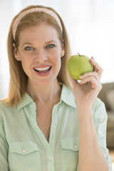 Happy Mature Woman Holding Granny Smith Apple At Home